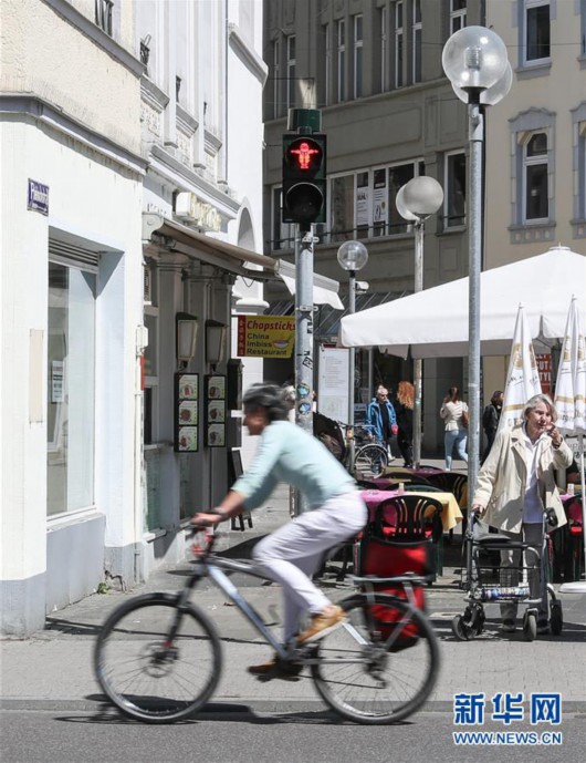5月4日，在德国特里尔，一名女子骑车经过一个使用马克思形象的交通信号灯。新华社记者单宇琦 摄